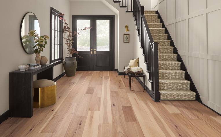 warm toned hardwood flooring in entryway with brown and gold accent furniture